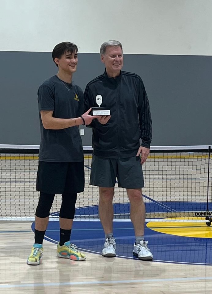 Ross Melbourne and his doubles partner holding a first-place pickleball trophy